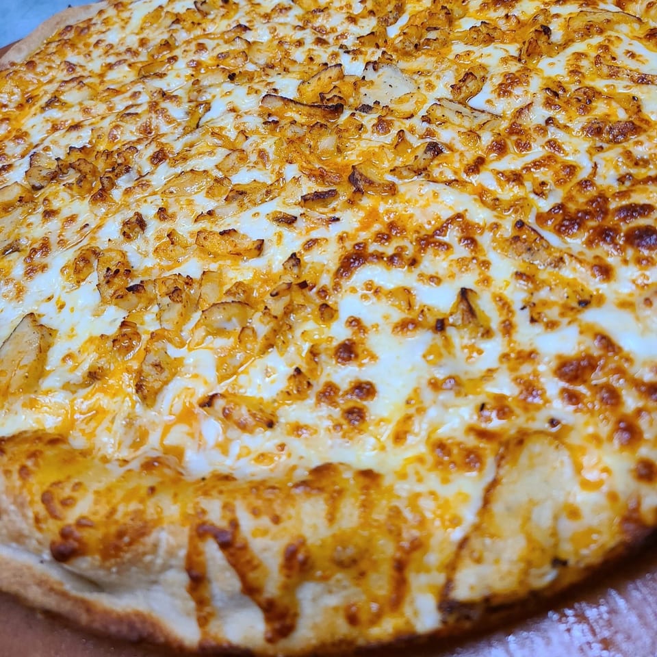 Close-up of a Pizza King pizza with melted cheese and chicken pieces.