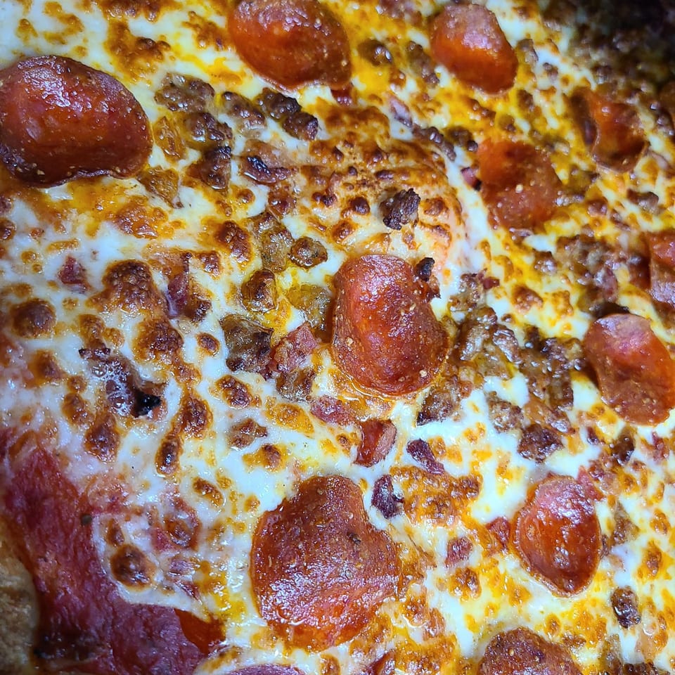 Close-up of a Pizza King pizza with melted cheese, pepperoni, and sausage.